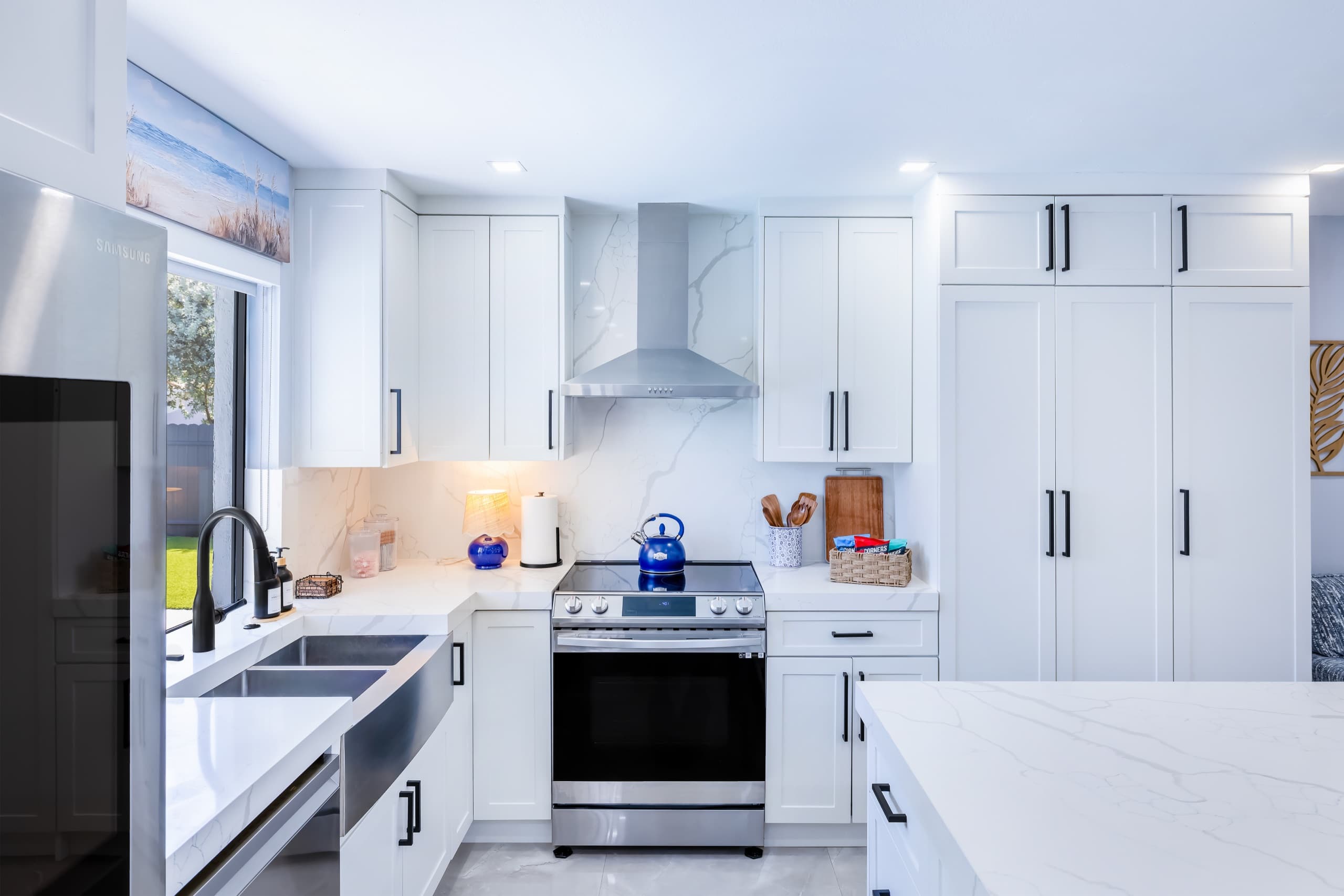 Range with a stainless hood and a white backsplash, flanked by white cabinets.