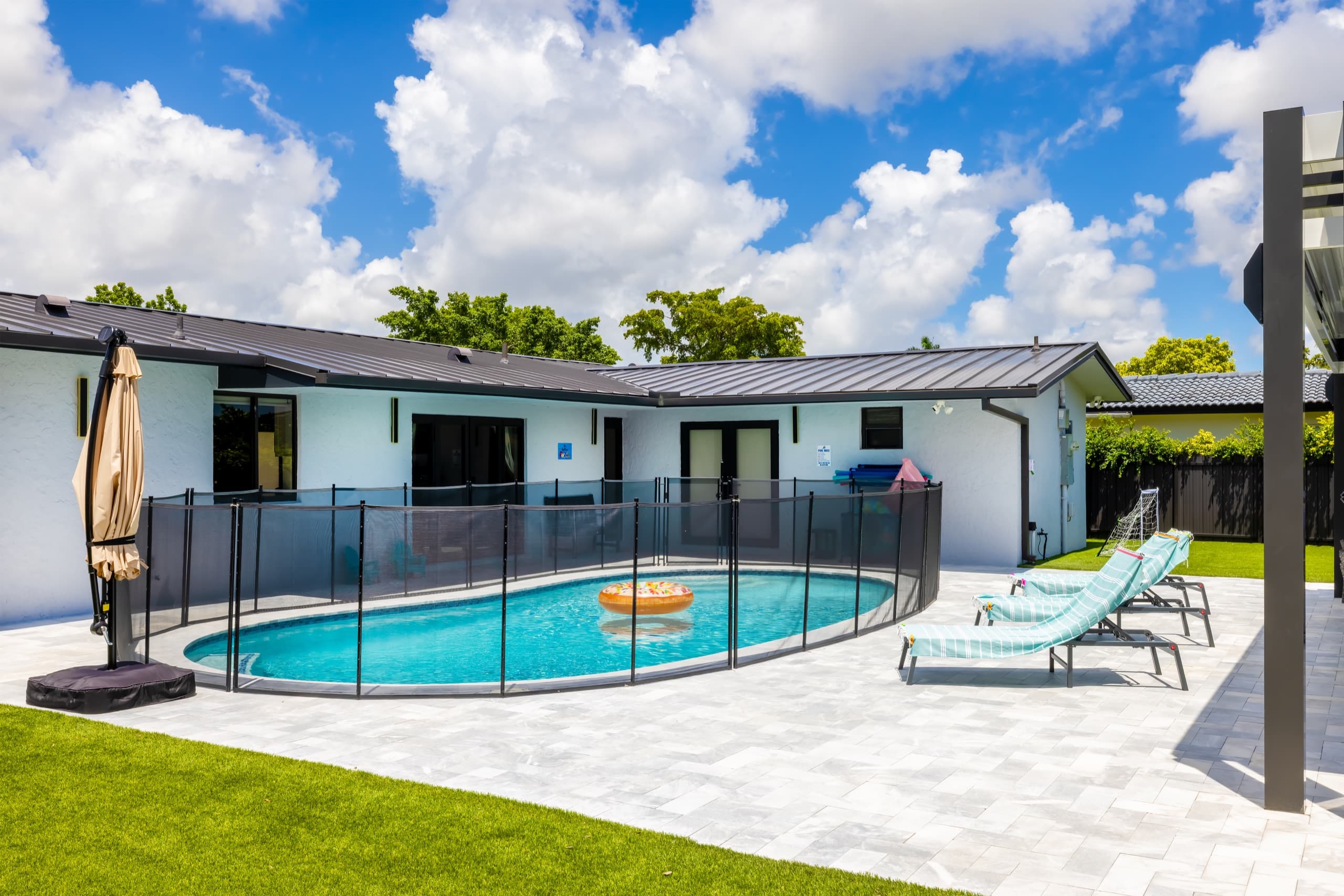 Pool with turquoise water and loungers, with the back of the house behind it.