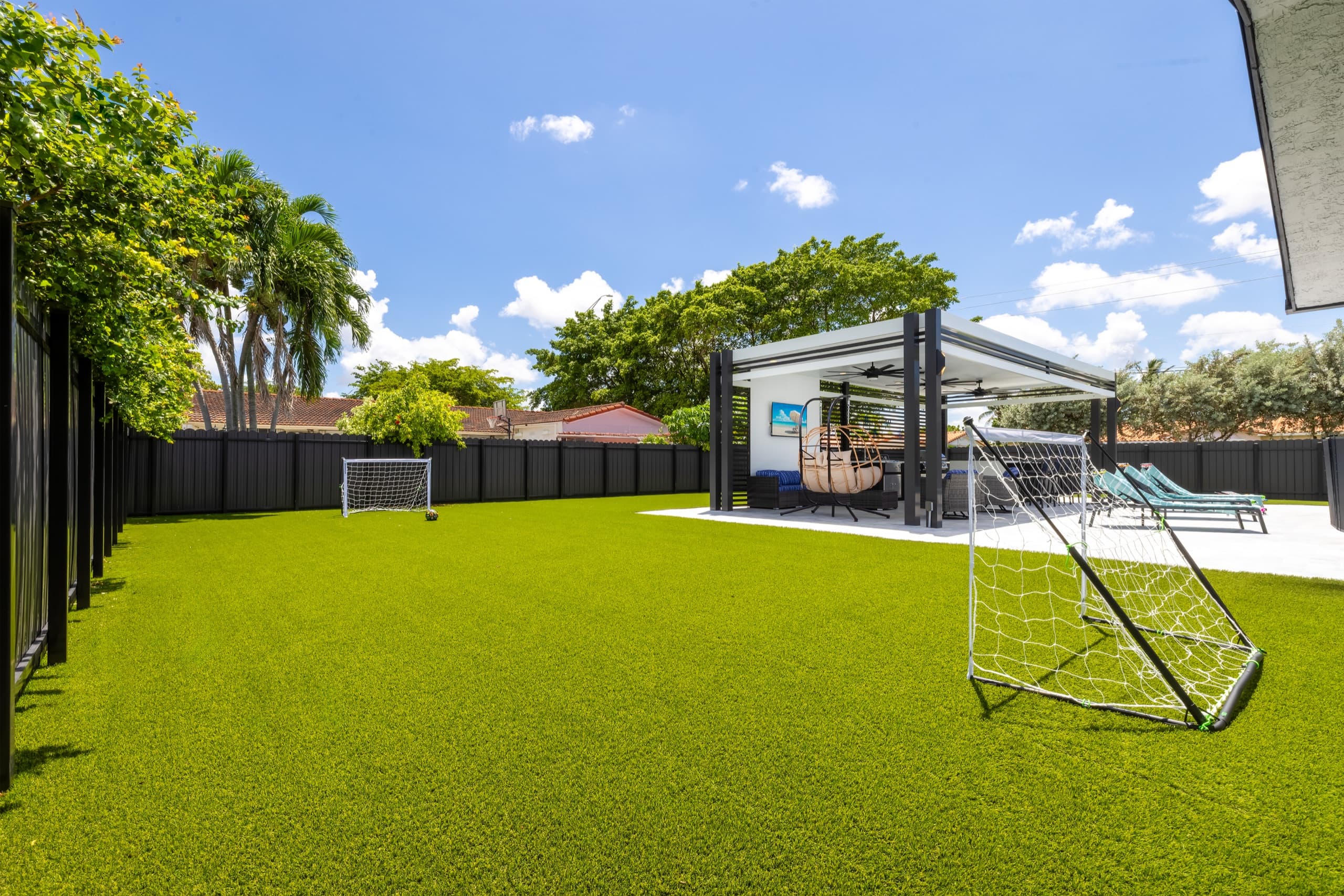 Open lawn with two small soccer goals, the pavilion and a charcoal privacy fence.