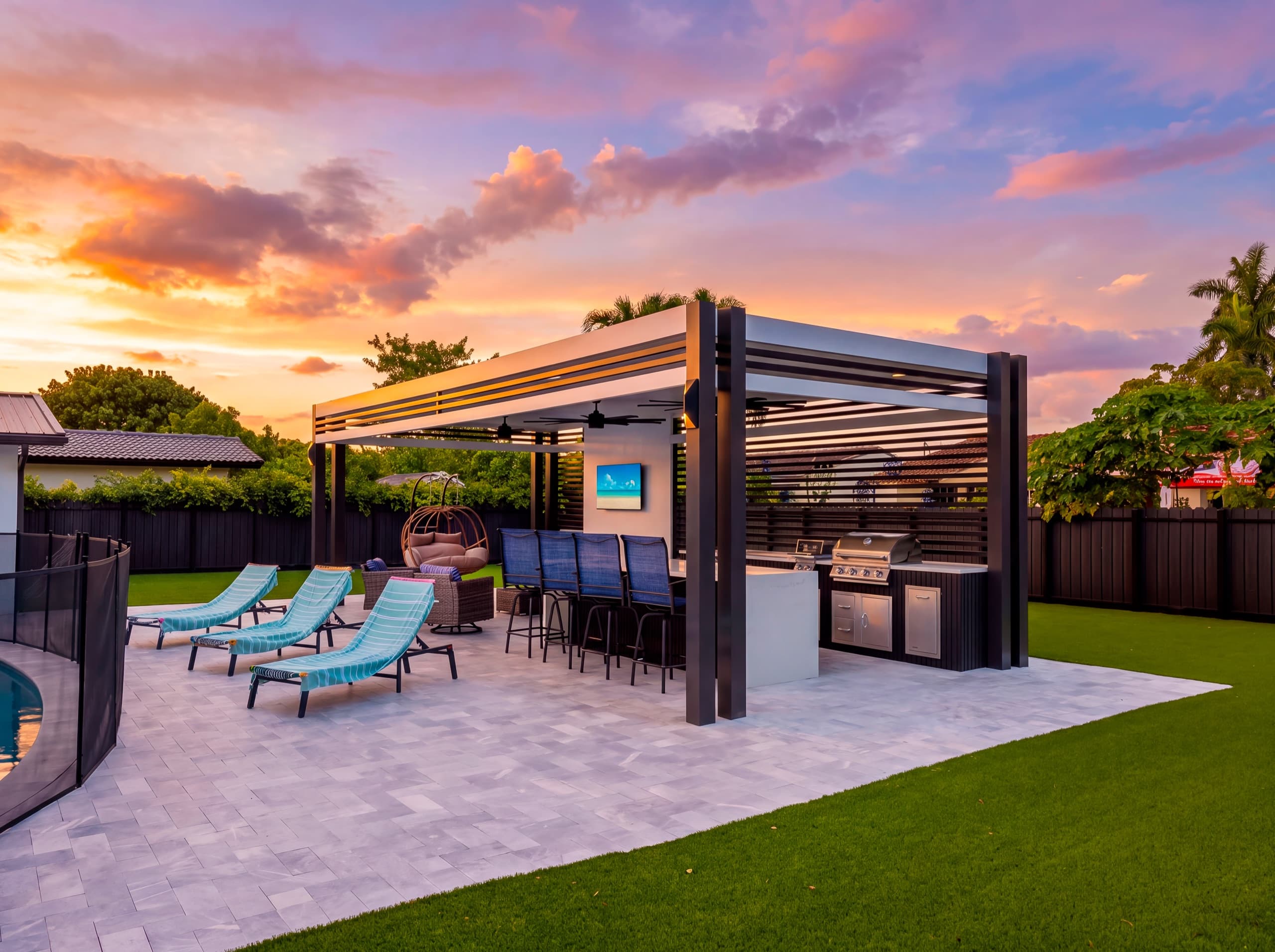 The pavilion at dusk with its lights on, loungers on the deck and a curve of the pool.