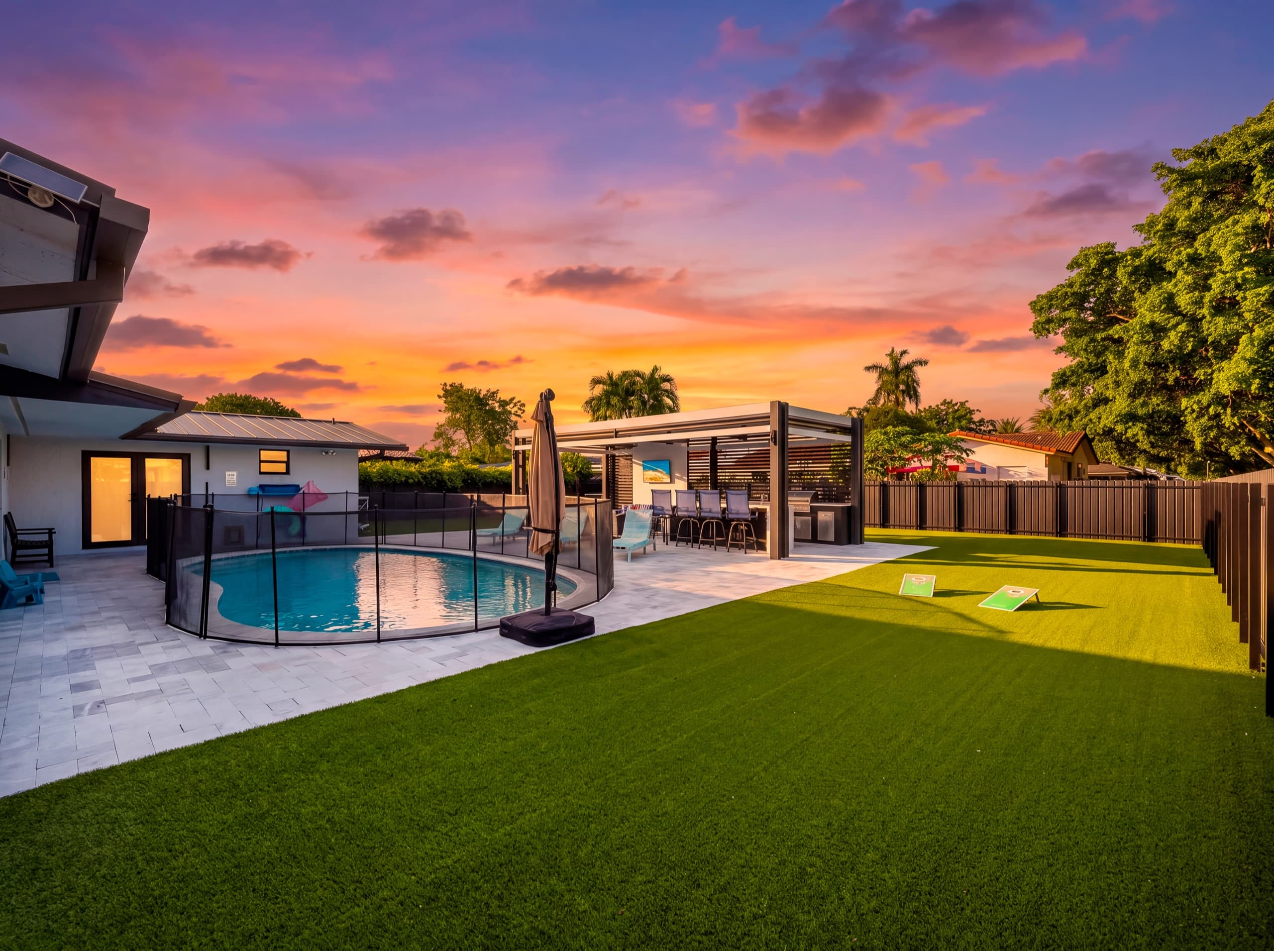The same backyard at dusk, with the lights on in the house and the pavilion.
