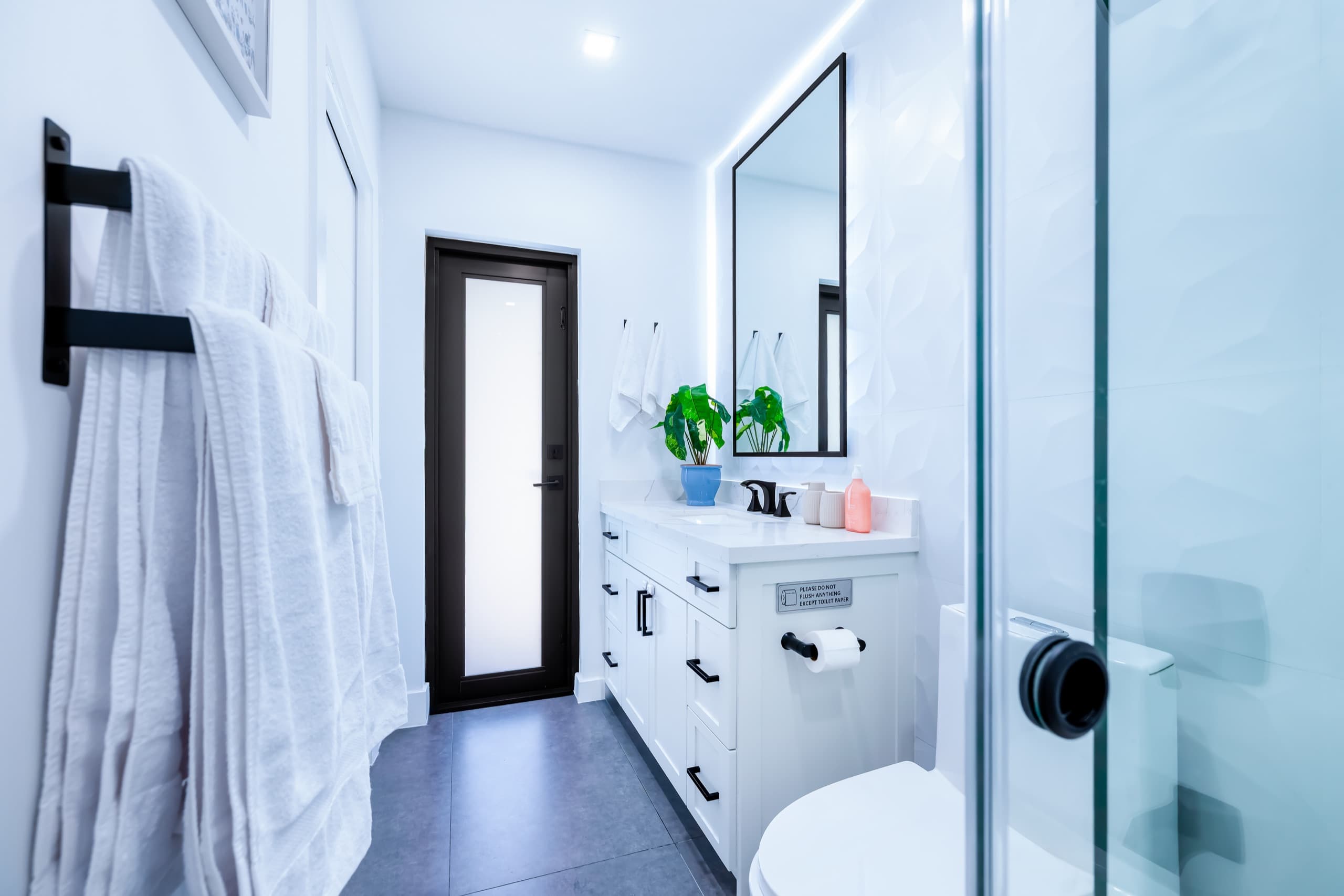 Bathroom seen from beside the tub toward the vanity and a frosted-glass door.