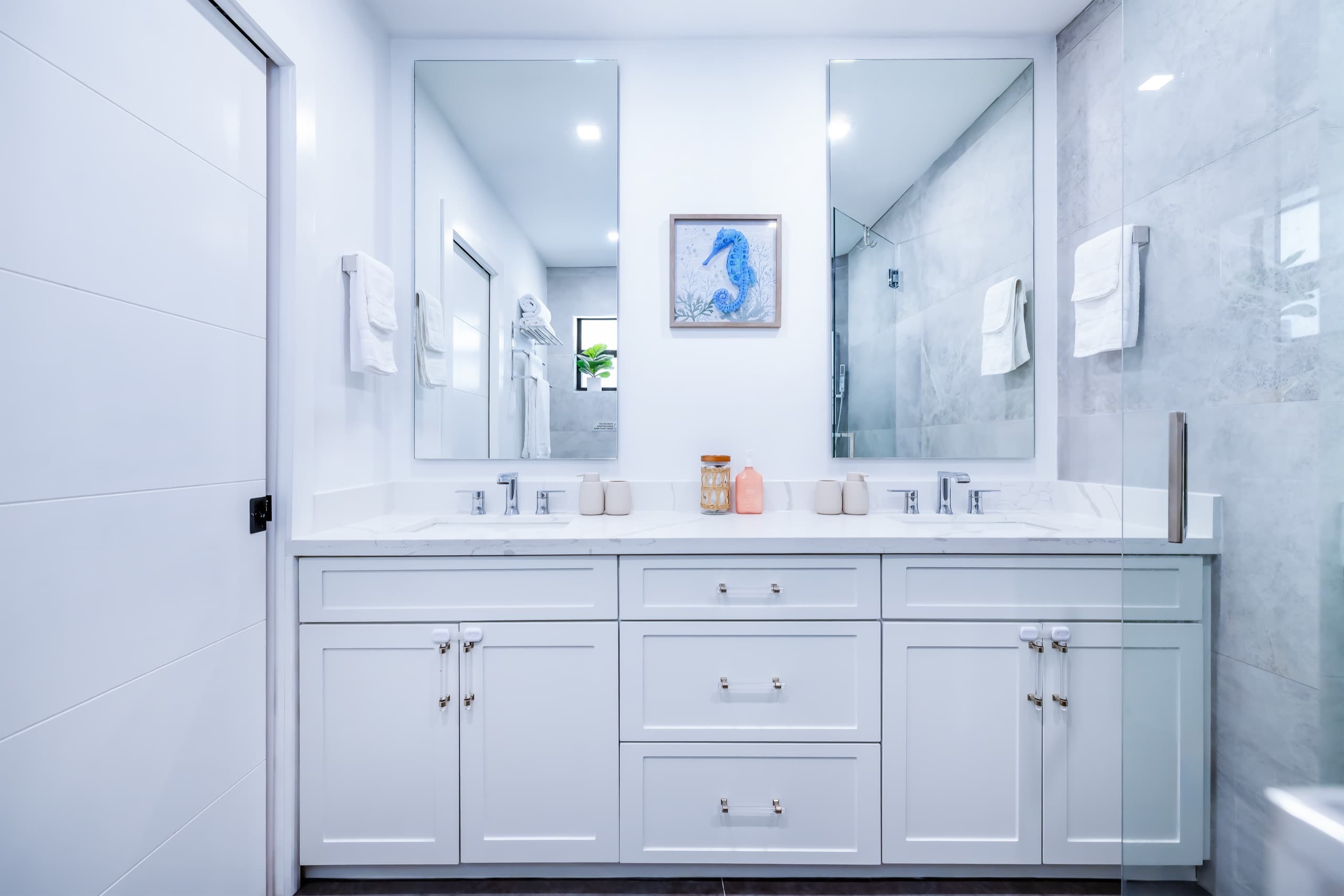 Double vanity with two sinks and two mirrors, with a seahorse print between them.