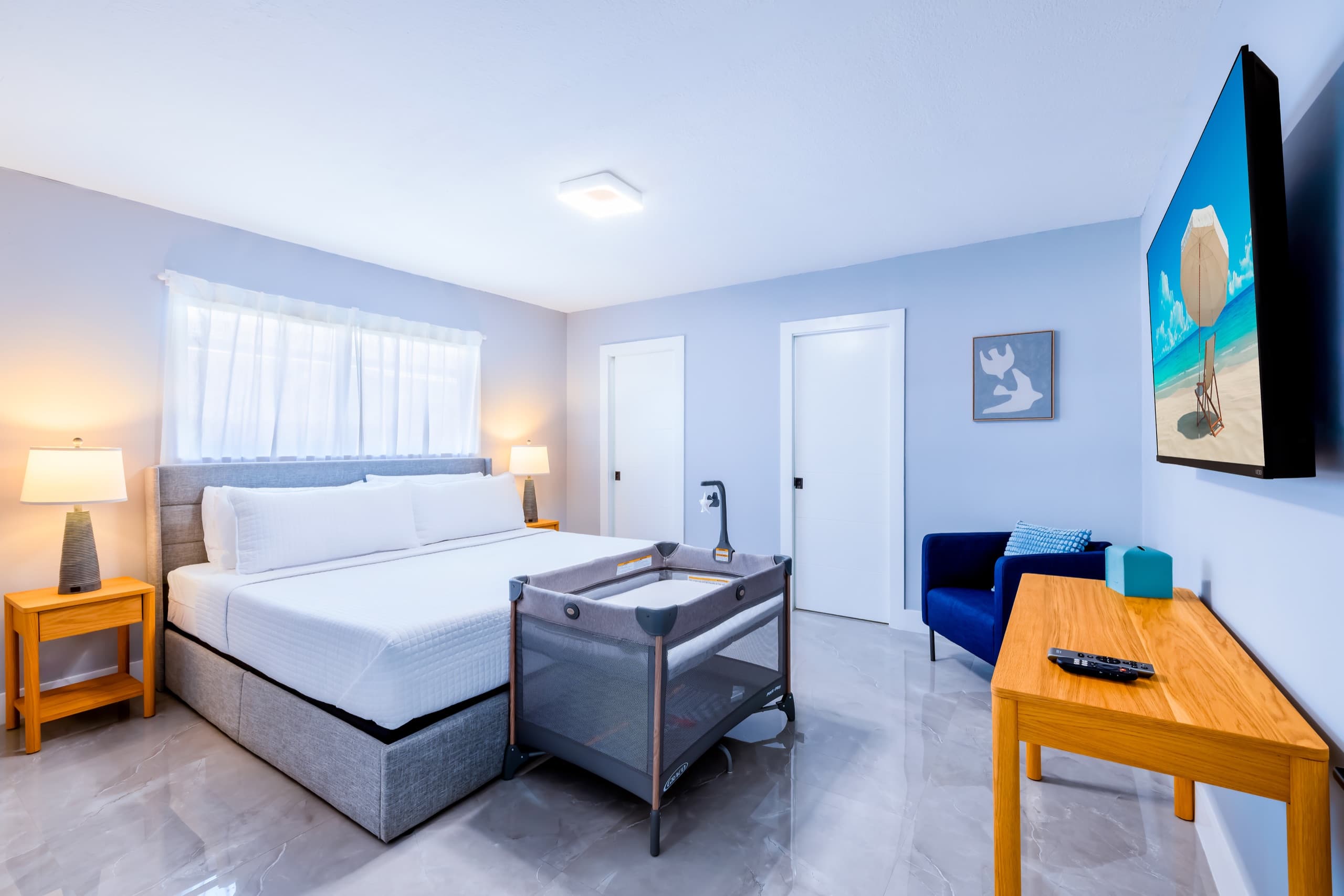 The same bedroom with a travel crib set up at the foot of the bed.