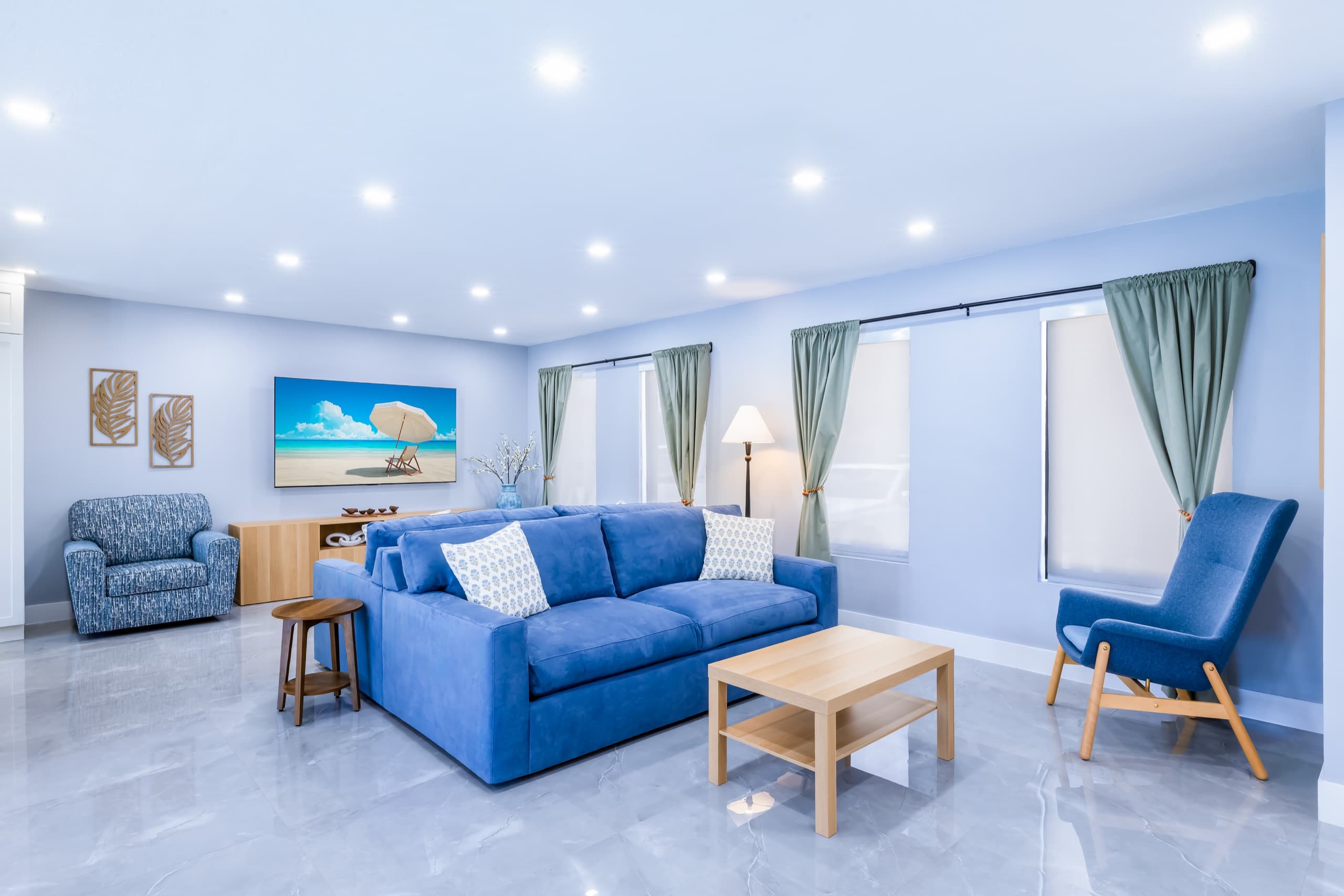 Blue sofa, wooden coffee table and blue armchair in front of a wall-mounted TV.